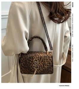 Détail du sac à main léopard avec logo métallique doré et gland porté par le modèle