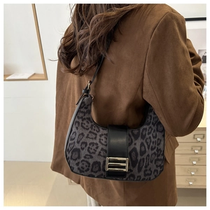 Detail of leopard print hobo bag with gold metal buckle on a brown suede jacket background