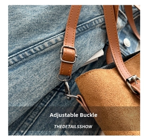 Detail of adjustable leather shoulder strap with gold metal buckle on a brown suede bag