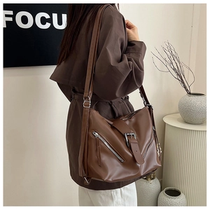 Detail of dark brown leather tote bag featuring silver zippers and bold buckle straps