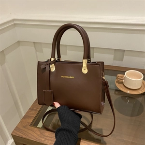 Minimalist dark brown leather tote bag with gold lettering shown in a stylish setting