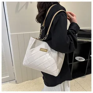 Detail of white quilted tote bag with golden chain and Fashion label on shoulder
