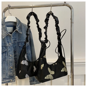 Detail of black silk shoulder bags with butterfly embroidery and ruched straps