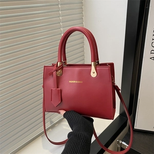 Minimalist dark red faux leather tote bag with gold lettering and top handles