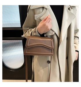 Detailaufnahme der braunen Vintage PU-Lederhandtasche mit Wellenprägung auf dem Deckel