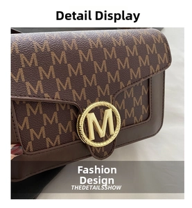 Dettaglio ravvicinato del tessuto jacquard marrone e della fibbia dorata con logo M della borsa