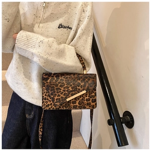 Close-up of leopard print crossbody bag featuring golden hardware and a matching strap