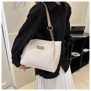 Detail of off-white quilted tote bag featuring a leather chain strap and fashion label
