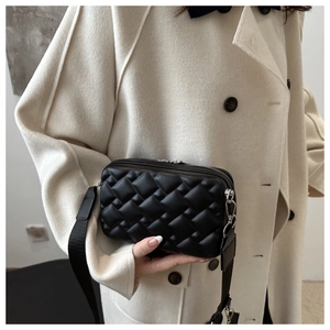 Detail of black quilted crossbody bag with woven texture and adjustable strap