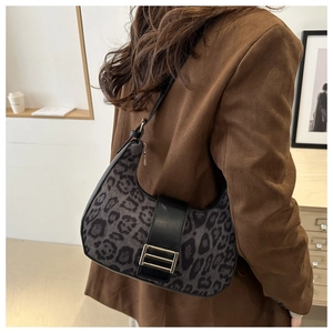 Detail of leopard print crescent bag with leather strap and golden buckle on shoulder