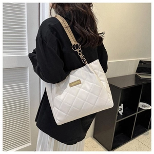 Detail of white quilted tote bag featuring gold chain strap and elegant rhombus stitching