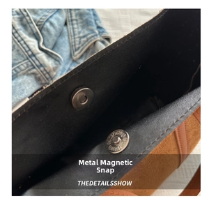 Detail view of the secure magnetic silver buckle on a brown frosted tote bag