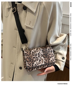 Detail der Leopard-Umhängetasche mit schwarzem Gurt auf einem beigen Trenchcoat