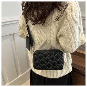 Detailed back view of a black quilted crossbody bag with small round coin purse attachment