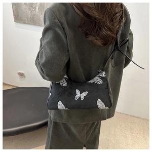 Close-up of black butterfly embroidery on an elegant shoulder bag under the arm