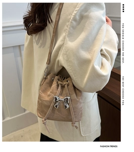 Detail of beige drawstring bucket bag with silver butterfly buckle and pleated texture