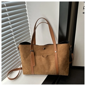 Detail of brown suede tote bag featuring silver hardware and a front pocket design