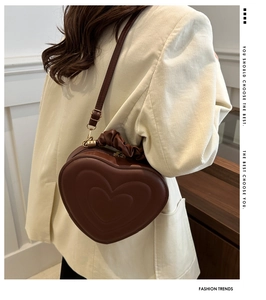 Detail of dark brown heart-shaped bag with embossed texture and pleated handle