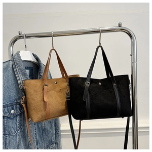 Detail of suede vintage tote bags in brown and black with leather straps and metal buckles