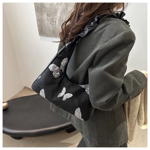 Detail of silver butterfly embroidery and ruffled leather strap on black hobo shoulder bag