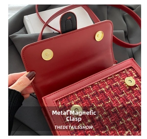 Detail of red tweed handbag featuring dual gold magnetic buckles and leather flap cover