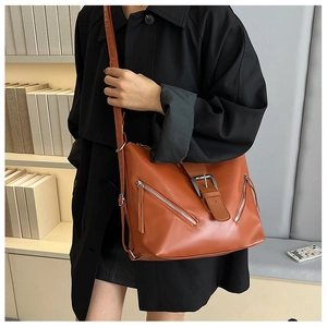 Detail view of a vintage caramel leather shoulder bag with decorative zips and buckle