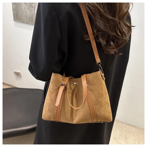 Detail view of brown faux suede tote bag with metal buckle and smooth leather trim