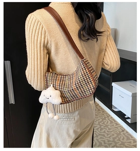 Detail of retro houndstooth shoulder bag with brown strap and cloud plush charm