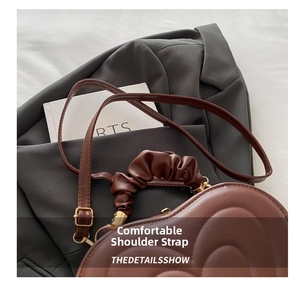 Detail of brown heart-shaped bag with quilted texture and ruched cloud handle