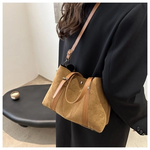 Detailed view of camel suede-like tote bag with brown leather straps worn over a black blazer