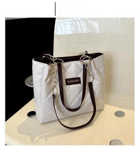 Detail of white quilted tote bag with coffee leather straps and golden chain accents
