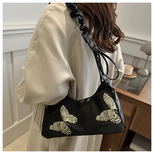 Detail view of black velvet shoulder bag with golden butterfly embroidery and pleated strap