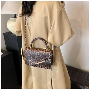 Sac bandoulière à imprimé léopard avec détails dorés porté par un mannequin en trench-coat