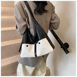Detail of stylish black leather and white sherpa patchwork large tote bag on a model