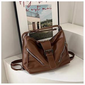 Detailed view of caramel brown tote bag featuring vintage metal buckles and zippers
