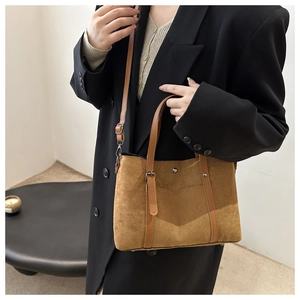 Detailed macro view of brown suede tote bag with metal studs and adjustable handle