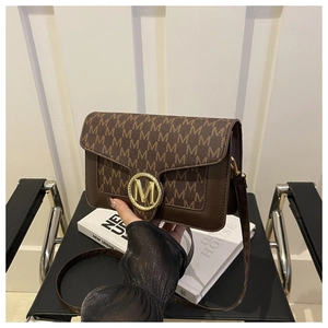 Détail de sac bandoulière marron vintage avec imprimé lettres et boucle métallique dorée
