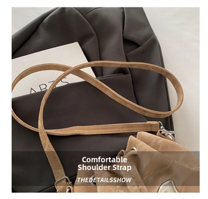 Close-up of stylish khaki bucket bag strap with silver metal buckle on textured leather