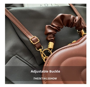 Detail of brown leather bag with golden buckle and stylish ruched handle design