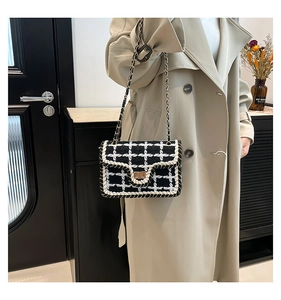 Dettaglio della trama in tweed a quadri bianchi e neri e della chiusura a scatto dorata