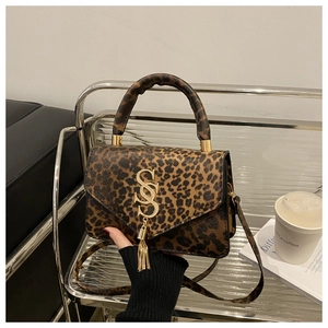 Détail du sac léopard avec logo SS doré et accessoire élégant à pompon sur le côté