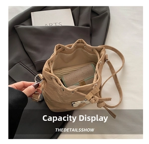 Detail view of khaki drawstring bucket bag showing interior capacity with phone and wallet