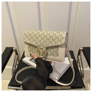 Détail du sac bandoulière crème avec boucle dorée en M et motif lettres imprimées