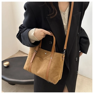 Brown suede tote bag with leather handles shown in a minimalist modern setting
