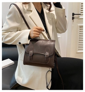 Detail of dark brown vintage satchel showing PU leather texture and double buckle straps
