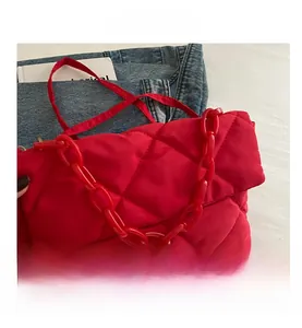 Détail du sac bandoulière rouge matelassé avec une élégante chaîne épaisse en acrylique