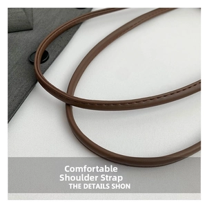 Detail of a brown leather shoulder strap with high-quality stitching on a minimalist bag