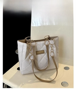 Close-up of quilted PU leather tote bag with gold chain strap and Fashion logo plate