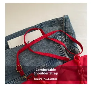 Détail du sac bandoulière matelassé rouge avec chaîne acrylique et boucle dorée