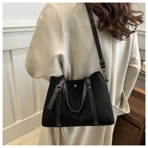 Detail of black canvas bucket bag with leather handles and silver metal hardware accents